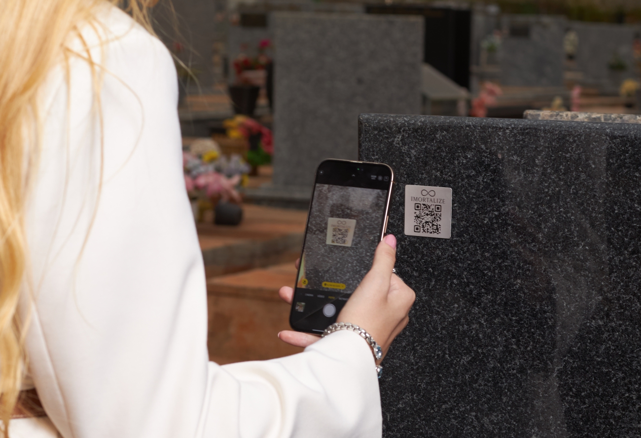 Pessoa escaneando QR Code em uma lápide — memorial Imortalize
